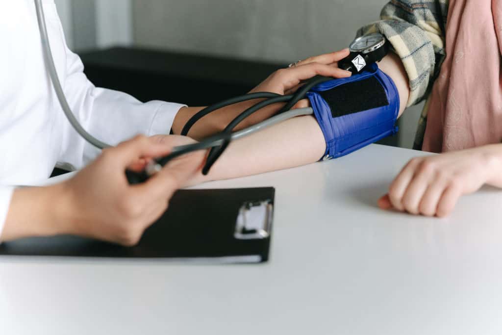 Wie kann Bluthochdruck kontrolliert werden? A healthcare worker measuring a patient s blood pressure using a sphygmomanometer
