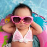 Sonnencreme und Sonnenhut am Strand, Newborn Baby Girl Wearing Sunglasses and a Bikini Top