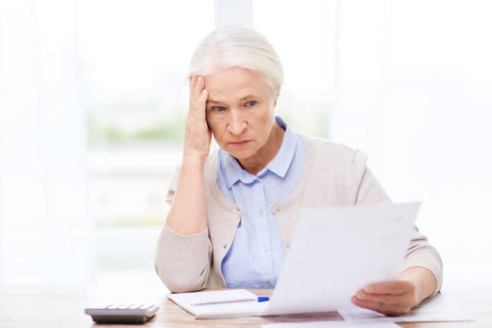 senior woman with papers and calculator at home