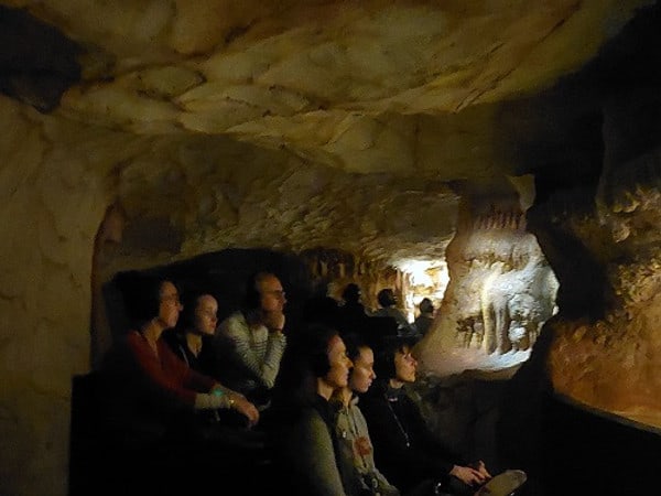 Besucher fahren in kleinen Wagen durch die Grotte