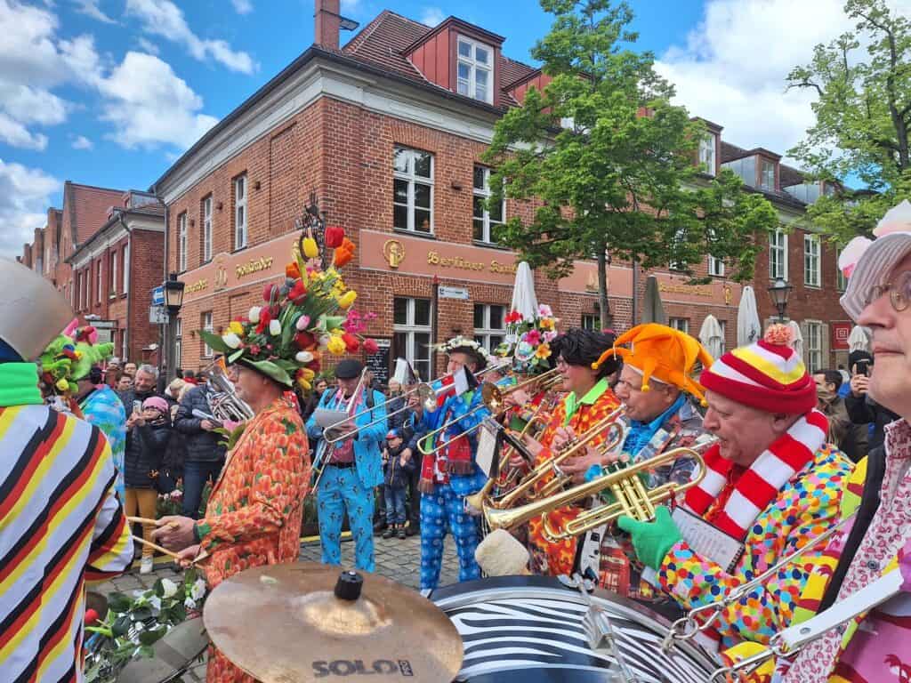 Bunt kostümierte Clowns spielen Trompete beim Karnevalsumzug.